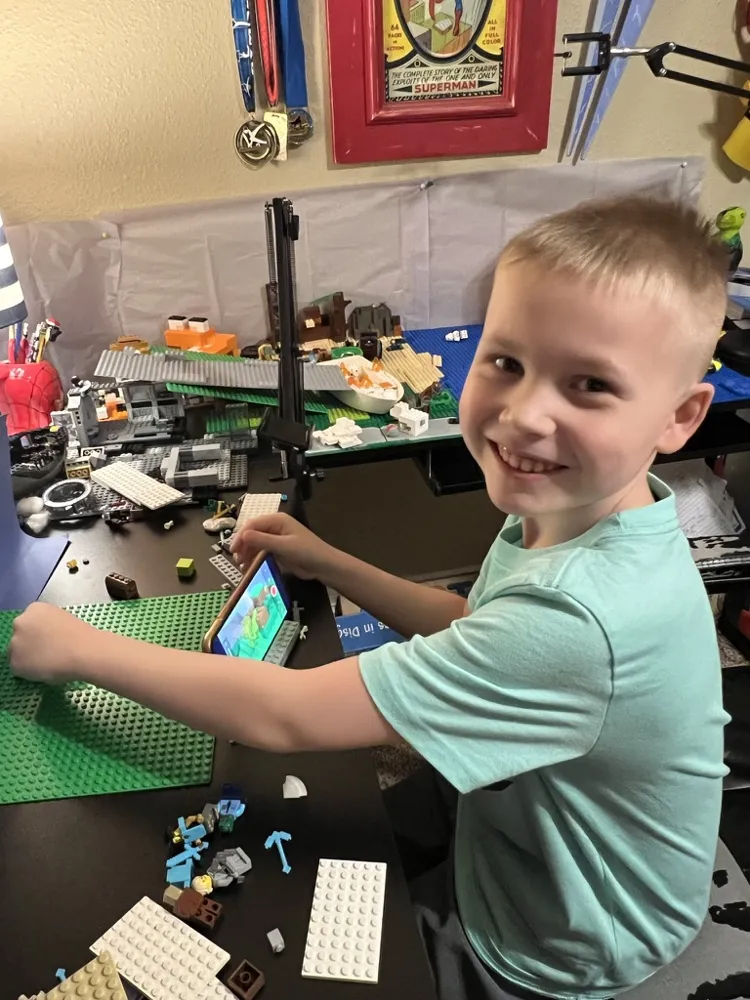 CJ smiling at his animation desk with his phone on a stand